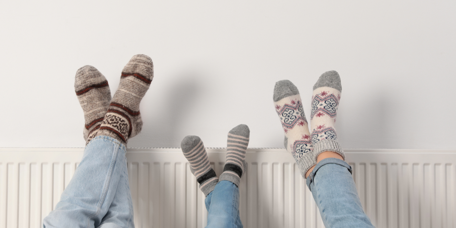 Three sets of feet cross legged on a radiator - Navigating Gas Boiler Installation: Your Ultimate 2024 Guide